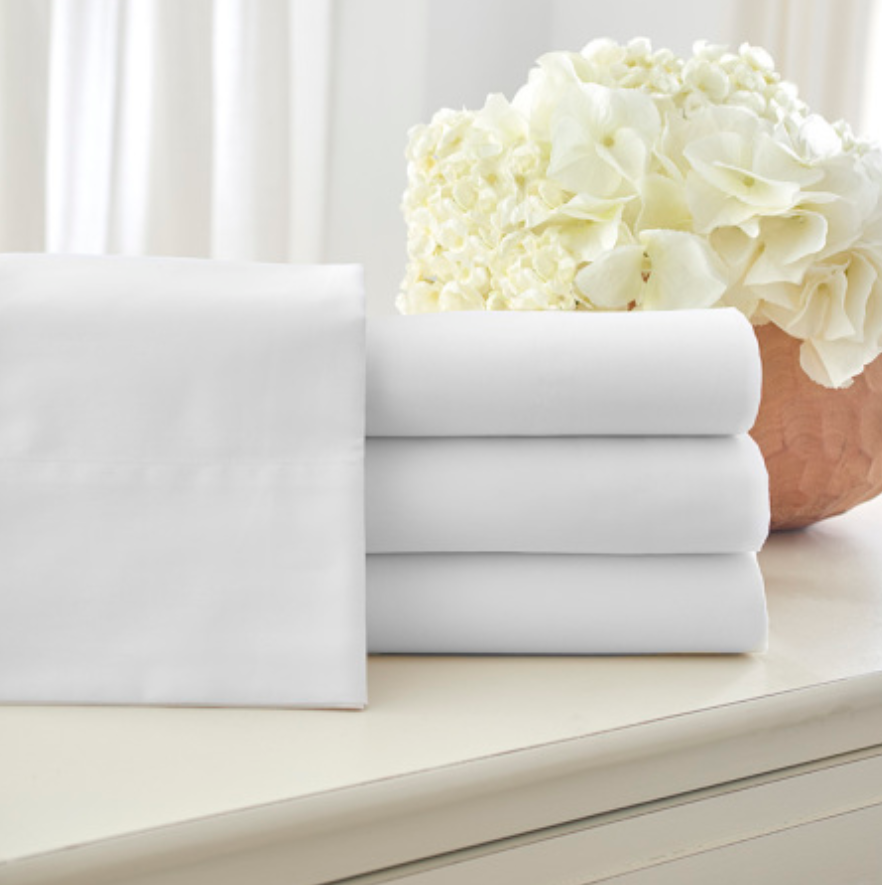 White bed sheets next to flowers
